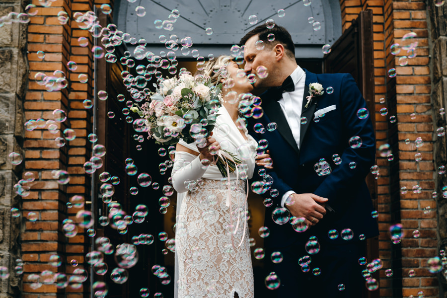 dwór kociołek wesele, para młoda wychodzi z kościoła, bańki mydlane zamiast konfetti
