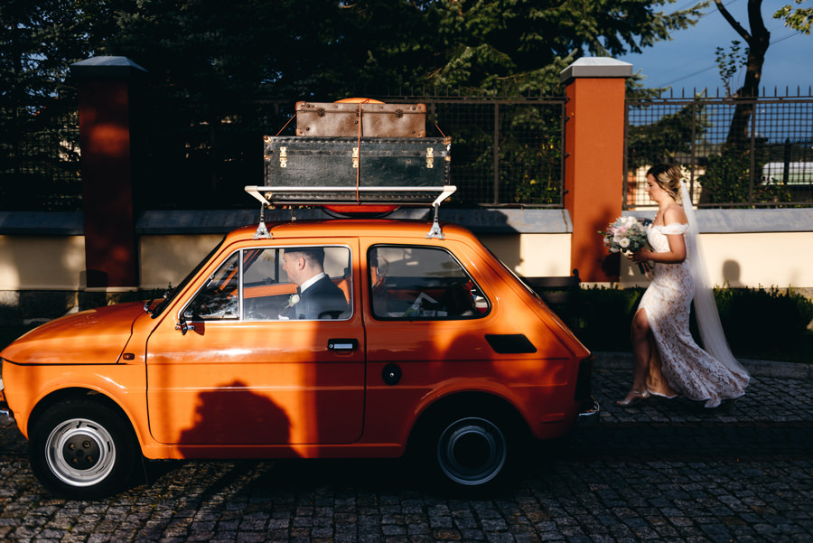 panna młoda wsiada do fiata 126p, zachód słońća, złota godzina, sesja w dniu ślubu