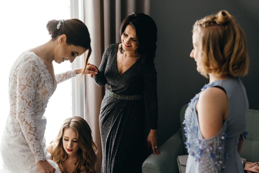 panna młoda przygotowuje się do ślubu, fotografia ślubna Bochnia, mama pomaga ubrać suknie pannie młodej
