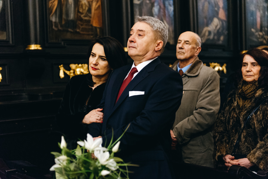 wzruszeni rodzice patrzą na przysięgę ślubną pary młodej